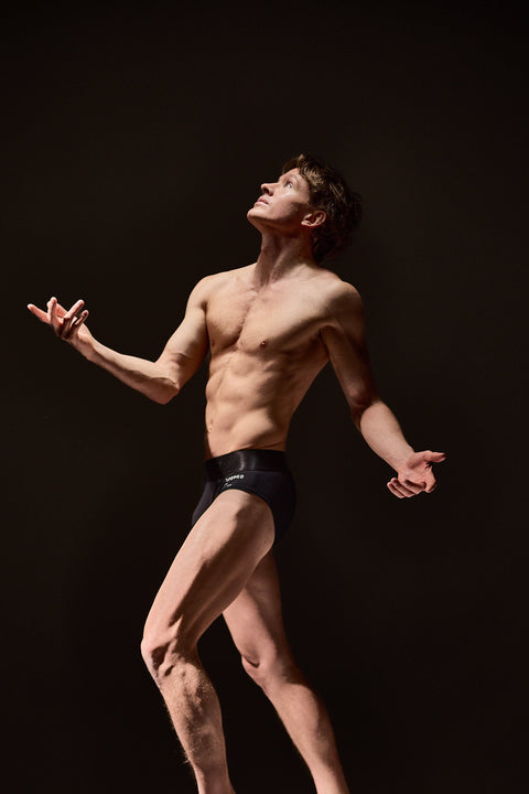 Shirtless man in black underwear against a dark background