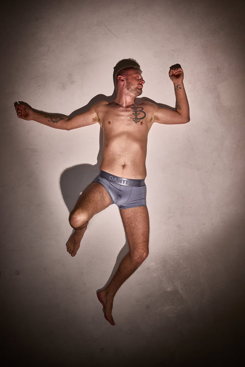 Man in gray underwear posing against a plain background