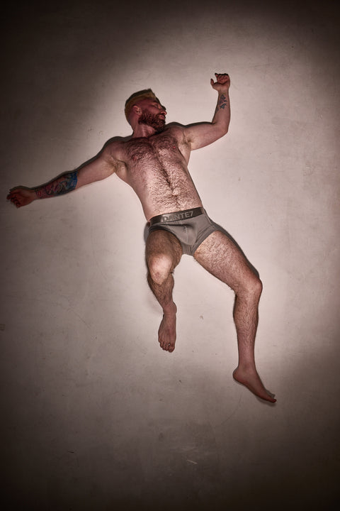 Man in underwear levitating against a plain background