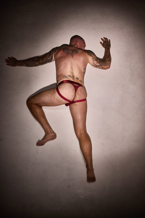 Man wearing a red thong against a plain background